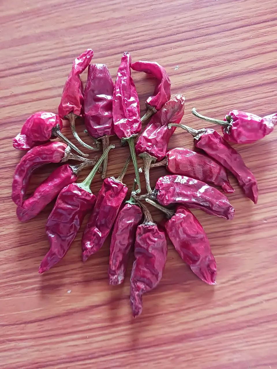 handful of dried chillies arranged on wooden surface