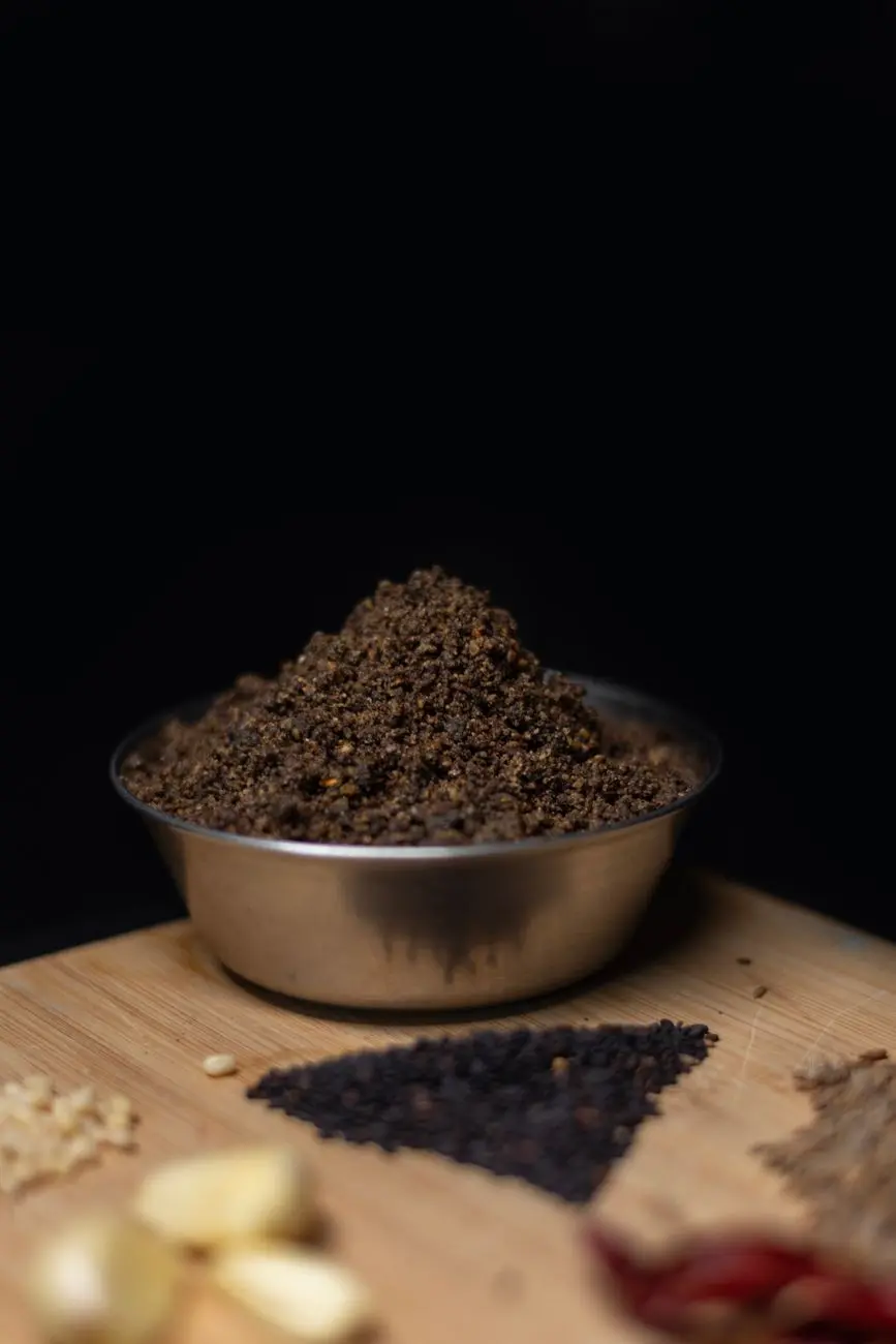 dark brown ground spice in metal bowl on wooden board